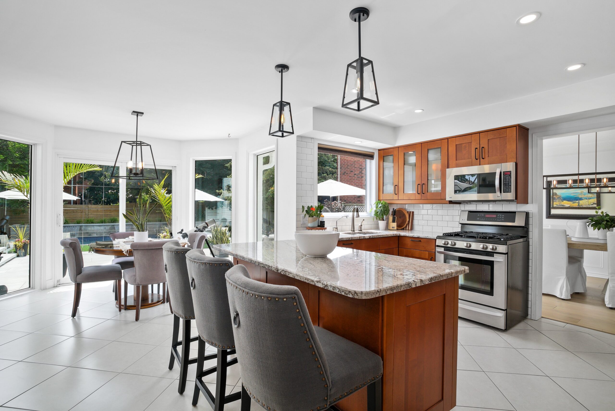 Kitchen with granite island, gas range, and warm wood cabinetry in Cambridge home