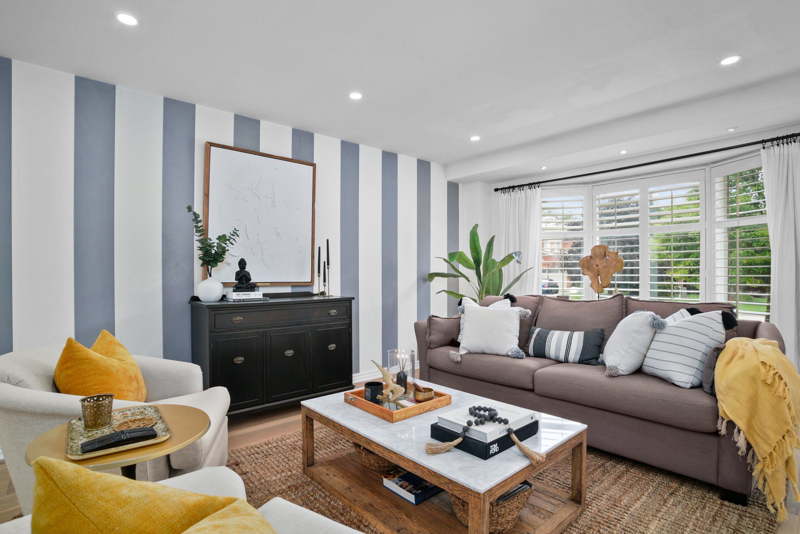 Living room with striped accent wall and bay window in Cambridge home