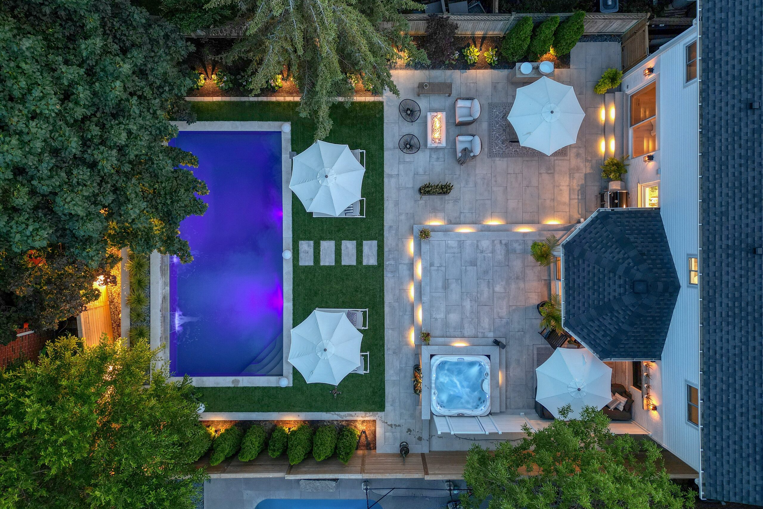 Twilight aerial view of Cambridge family home with pool, hot tub, and cabana