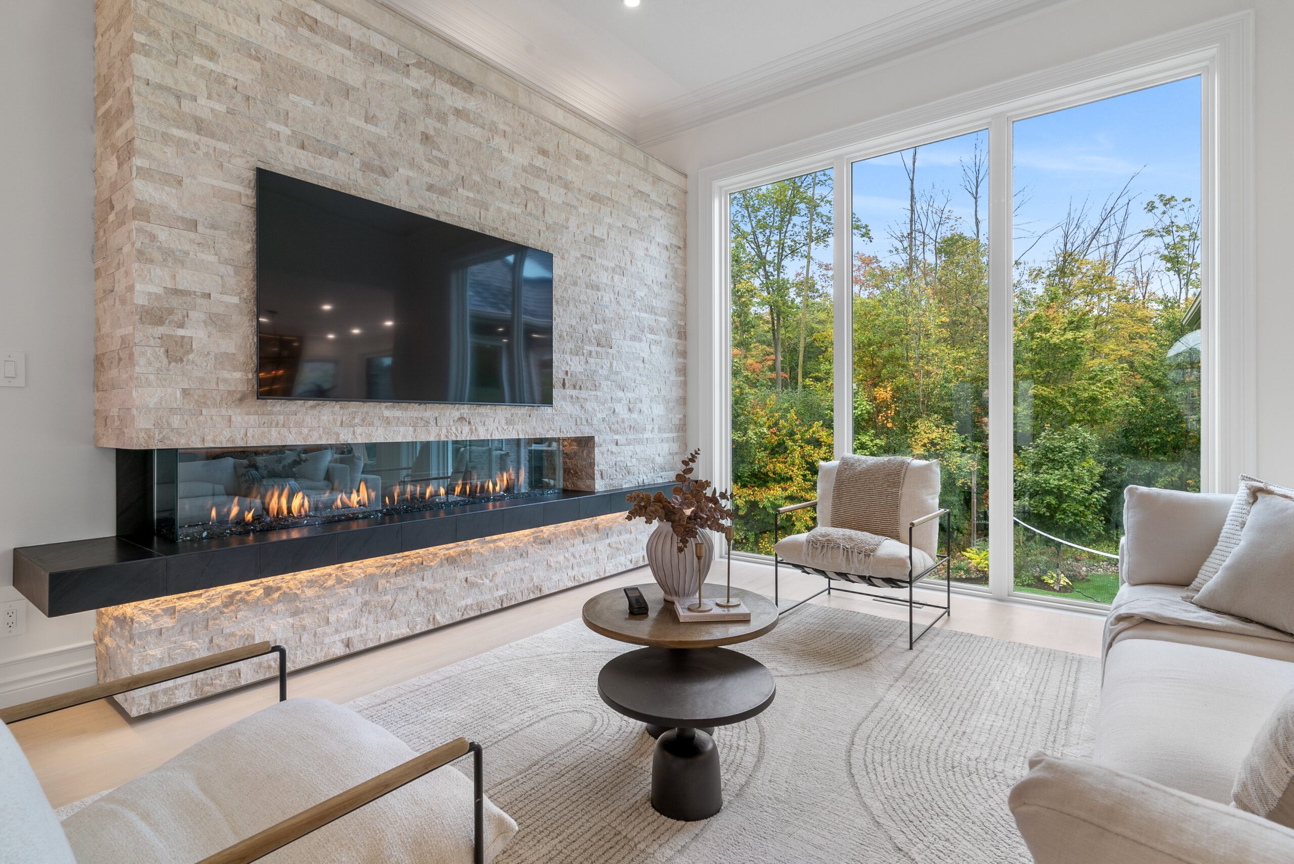 Living room with stacked stone fireplace and forest views in Heidelberg